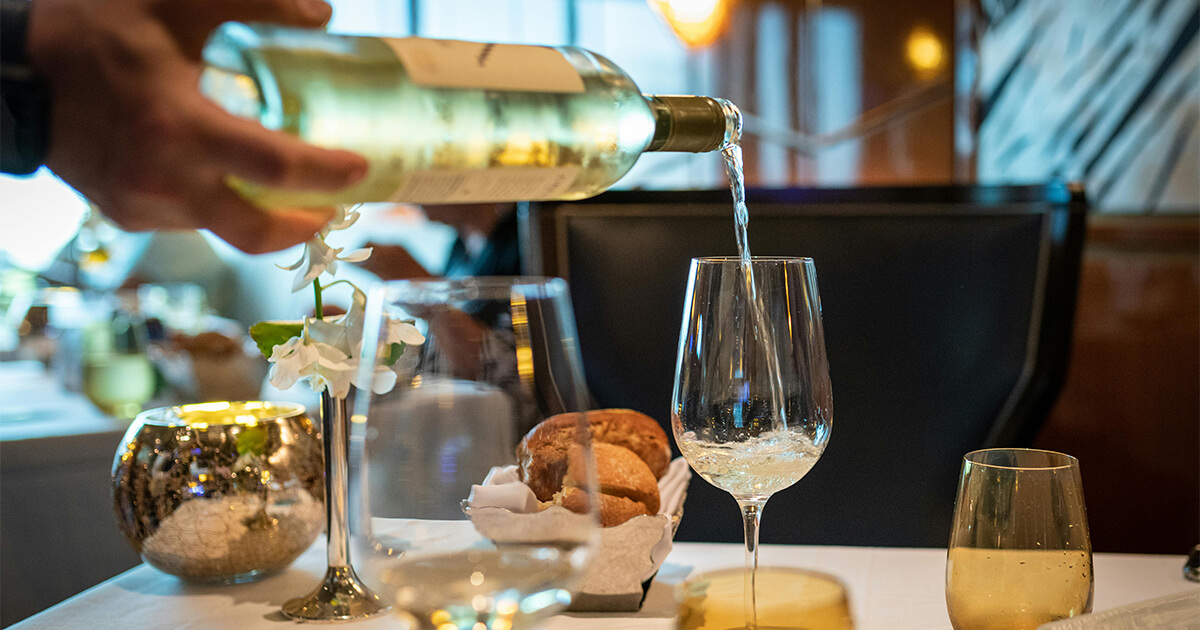 Weinflasche, die auf Glas gie&szlig;t